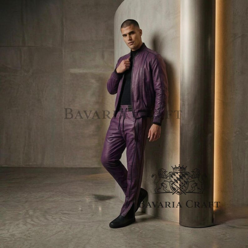 May include: A two-piece purple leather outfit, consisting of a bomber jacket and matching pants. The jacket has a black collar and cuffs. The pants have a vertical seam down the front of each leg. The outfit is worn with a black top and shoes.