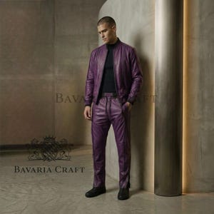 May include: A two-piece purple leather outfit, consisting of a bomber jacket and matching pants. The jacket has a zip-up front and the pants have a drawstring waist. The outfit is worn with a black top and black shoes. The brand name "BAVARIA CRAFT" is visible.