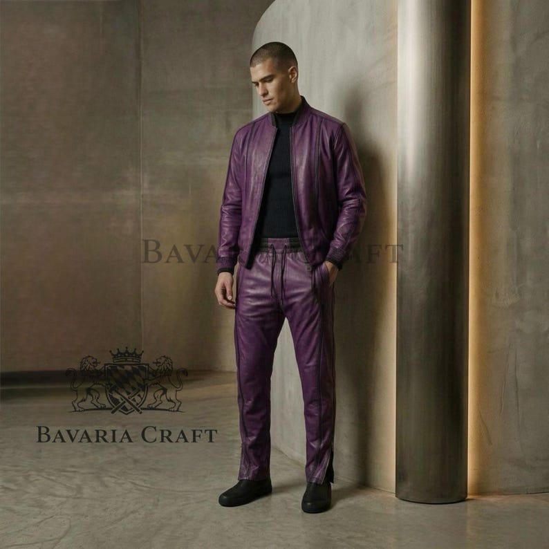 May include: A two-piece purple leather outfit, consisting of a bomber jacket and matching pants. The jacket has a zip-up front and the pants have a drawstring waist. The outfit is worn with a black top and black shoes. The brand name "BAVARIA CRAFT" is visible.