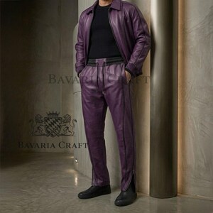 May include: A two-piece purple leather outfit, including a jacket and pants. The jacket has a collar and zipper, and the pants have a drawstring waist and zippers at the ankles. The outfit is paired with black shoes. The brand name "Bavaria Craft" is visible.