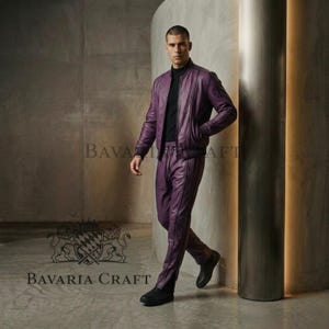 May include: A purple leather bomber jacket and matching pants. The jacket has a zip closure and side pockets. The pants have a straight leg design with a vertical seam. The outfit is worn with a black turtleneck and black shoes. The brand name "BAVARIA CRAFT" is visible.