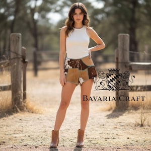 May include: A white sleeveless ribbed tank top paired with brown and white cow-print patchwork shorts featuring a lace-up front detail and brown ankle boots. The image includes a heraldic crest logo and the text Bavaria Craft.