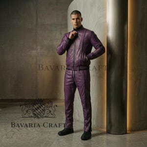 May include: A two-piece purple leather tracksuit. The jacket has a zip-up front and the pants have a straight leg design. The outfit is worn with black shoes. The brand name "BAVARIA CRAFT" is visible in the image.