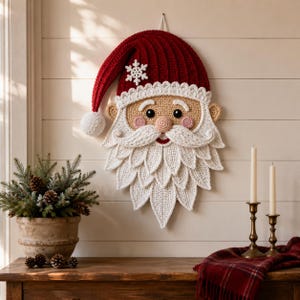 Peut inclure: Une décoration murale en crochet représentant le Père Noël, avec un bonnet rouge foncé orné d'un pompon blanc et d'un flocon de neige. Le visage beige présente des yeux noirs, des joues roses, un nez rond et une barbe blanche texturée.