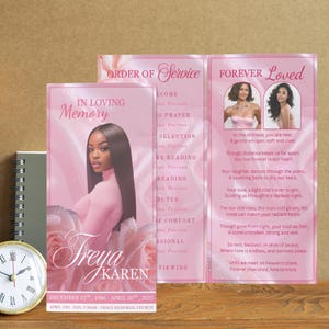 May include: A memorial service program with a pink and white floral design. The front features a photo of a woman and the names "Freya Karen". The program includes text such as "In Loving Memory" and "Forever Loved". A clock and a notebook are in the background.