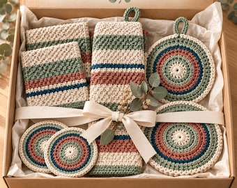 May include: A gift box containing handmade crochet kitchen items including rectangular cloths, a long towel with a hanging loop, and circular coasters. The items feature striped patterns in cream, sage green, terracotta, and dark blue. Text reads HANDMADE KITCHEN GIFT and DIGITAL CROCHET PATTERN.