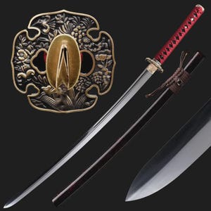 May include: A Japanese katana sword with a polished steel blade and a red handle. The sword features a decorative bronze tsuba guard with floral and leaf patterns. The scabbard is dark brown.