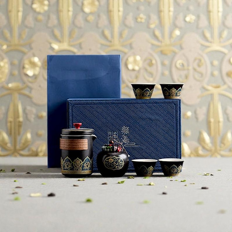 Peut inclure: Un service &agrave; th&eacute; noir et dor&eacute; avec une th&eacute;i&egrave;re, des tasses et un petit r&eacute;cipient assortis. L'ensemble &agrave; th&eacute; est pr&eacute;sent&eacute; devant une bo&icirc;te bleue. L'ensemble &agrave; th&eacute; pr&eacute;sente des motifs floraux dor&eacute;s. Le fond est un motif floral dor&eacute; et gris.