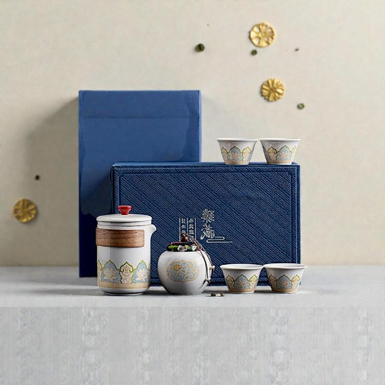 Peut inclure: Un service &agrave; th&eacute; traditionnel avec un design blanc et dor&eacute;, comprenant une th&eacute;i&egrave;re, un petit pot et plusieurs tasses, pr&eacute;sent&eacute; dans un coffret cadeau bleu. L'ensemble pr&eacute;sente des motifs complexes et un accent rouge sur le couvercle de la th&eacute;i&egrave;re.