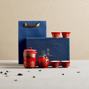 Peut inclure: Un service &agrave; th&eacute; rouge et dor&eacute; avec une th&eacute;i&egrave;re, des tasses et un petit pot assortis. L'ensemble est pr&eacute;sent&eacute; avec une bo&icirc;te et un sac cadeaux bleus. Le service &agrave; th&eacute; pr&eacute;sente un motif d&eacute;coratif.