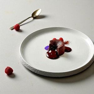 Pode incluir: Uma caneca de cerâmica branca com uma alça preta e o texto "But First, Coffee" em negrito preto. A caneca está cheia de um líquido escuro, provavelmente café, e está sobre uma superfície clara.