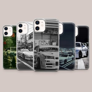 Puede incluir: Una colección de cinco fundas para teléfono con diseños de coches. Las fundas muestran imágenes de varios coches deportivos en diferentes entornos, incluyendo paisajes urbanos y escenas nocturnas. Las fundas tienen un diseño transparente y protector.