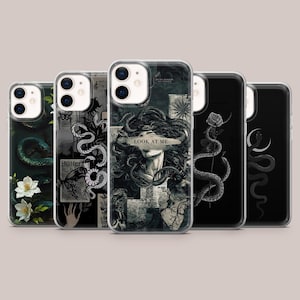 May include: A collection of five phone cases with unique designs. The cases feature dark backgrounds with illustrations of snakes, flowers, and Medusa. One case has the text "LOOK AT ME". The cases are made of clear plastic.