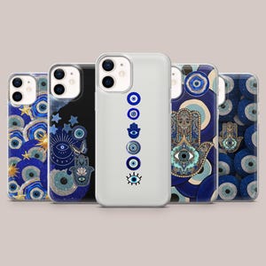 Könnte beinhalten: Eine Sammlung von fünf Handyhüllen mit verschiedenen Designs. Die Hüllen zeigen blaue und goldene Muster, Motive des bösen Blicks und Hamsa-Hand-Designs. Die Hüllen sind in verschiedenen Farben erhältlich, darunter transparent, schwarz und blau.