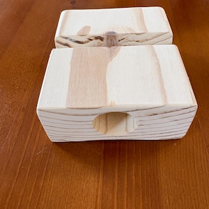 May include: Two rectangular wooden boxes with a natural wood grain finish. Each box has a rounded opening on one side. The boxes are made of light-colored wood and are displayed on a brown wooden surface.