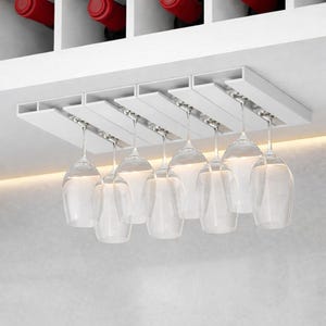Puede incluir: Un estante blanco para copas de vino montado en el techo con ocho copas de vino transparentes colgando. El estante es de madera blanca y tiene un diseño moderno. Las copas de vino están suspendidas por soportes metálicos plateados.