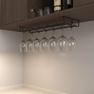 Può includere: Un portabicchieri in metallo nero installato sotto un mobile in legno, che contiene otto calici trasparenti. I bicchieri sono sospesi a testa in giù, mostrando la loro forma elegante. Il mobile è marrone scuro e lo sfondo è di colore neutro.