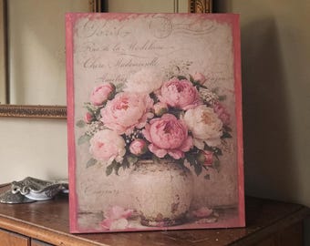 Puede incluir: Impresión floral enmarcada con un ramo de peonías rosas y blancas en un jarrón blanco desgastado. El fondo tiene escritura descolorida y un borde rosa. La impresión evoca una estética vintage y romántica.
