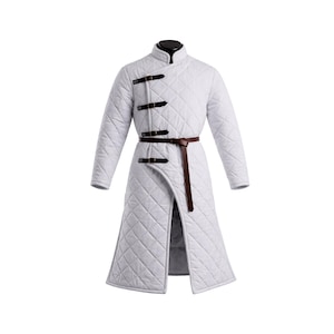 May include: A white quilted coat with a stand-up collar and long sleeves. The coat features a brown leather belt and three black leather straps with buckles. The coat has a diamond pattern and a front slit, creating a medieval or historical aesthetic.