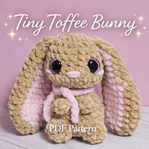 Puede incluir: Un conejito de ganchillo en tonos beige y rosa, con grandes ojos negros y una bufanda rosa. El texto "Tiny Toffee Bunny" se muestra encima del conejito, y "PDF Pattern" debajo. El conejito tiene orejas largas y caídas.