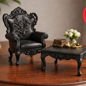 May include: Miniature black ornate chair and table set with a small table holding a vase of white flowers and books. The chair has a detailed back and armrests. The set is on a wooden surface.