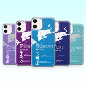 Puede incluir: Una colección de fundas para teléfonos con el logotipo de Red Bull y varios nombres de edición. Las fundas son en tonos morados, azules y turquesas, con texto que indica sabores como Juneberry e Iced Vanilla Berry. El logotipo de Red Bull se muestra de forma destacada.
