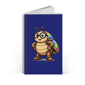 Puede incluir: Un cuaderno con espiral con una cubierta azul que presenta un personaje de escarabajo de dibujos animados con gafas y un ala de color arcoíris. El escarabajo está de pie con los brazos a los lados. El cuaderno está abierto.
