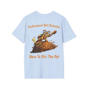 May include: Light blue t-shirt with a cartoon illustration of a bug stirring a pile of brown material with a wooden spoon. The text "Professional Shit Disturber" and "Born To Stir The Pot" are printed above and below the graphic.