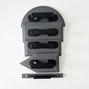 Peut inclure: Ensemble de truelles de plâtrage grises avec des poignées noires, disposées verticalement sur fond blanc. Les truelles présentent différentes formes, dont un dessus arrondi, des formes rectangulaires et triangulaires.