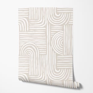May include: A roll of wallpaper with a repeating pattern of white brushstroke lines and curved shapes on a beige background. The design includes horizontal, vertical, and curved lines, creating a modern, abstract aesthetic.