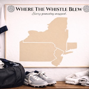 Puede incluir: Una exhibición temática de voleibol con un mapa enmarcado del estado de Nueva York con el texto "Where The Whistle Blew". Incluye una camiseta blanca con el número 11, una bolsa de lona negra, zapatillas grises, un voleibol y una toalla.