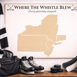 Puede incluir: Una exhibición temática de hockey con una camiseta, un mapa de Nueva York, palos de hockey, patines, un casco y discos. El mapa enmarcado tiene el texto "Where The Whistle Blew".
