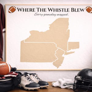 Puede incluir: Un mapa enmarcado del estado de Nueva York con el texto "Where The Whistle Blew" y "Every gameday mapped". Una camiseta granate con el número 23 cuelga a la izquierda. Balones de fútbol americano, un casco y tacos también son visibles.