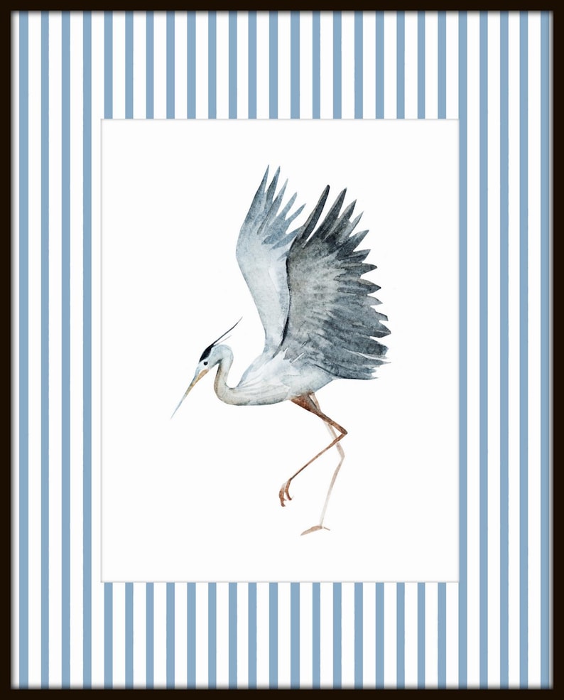 May include: A watercolor painting of a gray heron with its wings spread, standing on one leg, against a white background. The heron is depicted in a light blue frame with white stripes.