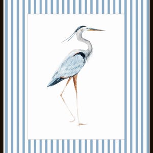 May include: A watercolor painting of a blue heron standing on one leg against a white background. The heron has a long neck and beak, and its feathers are a light blue color.
