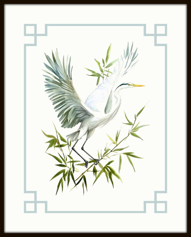 May include: Watercolor painting of a white heron with outstretched wings, perched on green bamboo branches. The bird has a yellow beak and gray-green wing feathers. The artwork is framed with a light blue border and a dark brown frame.