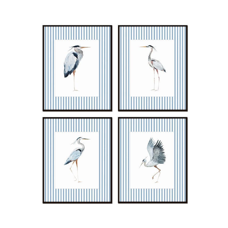 May include: Set of four framed prints featuring watercolor illustrations of blue herons on a blue and white striped background.
