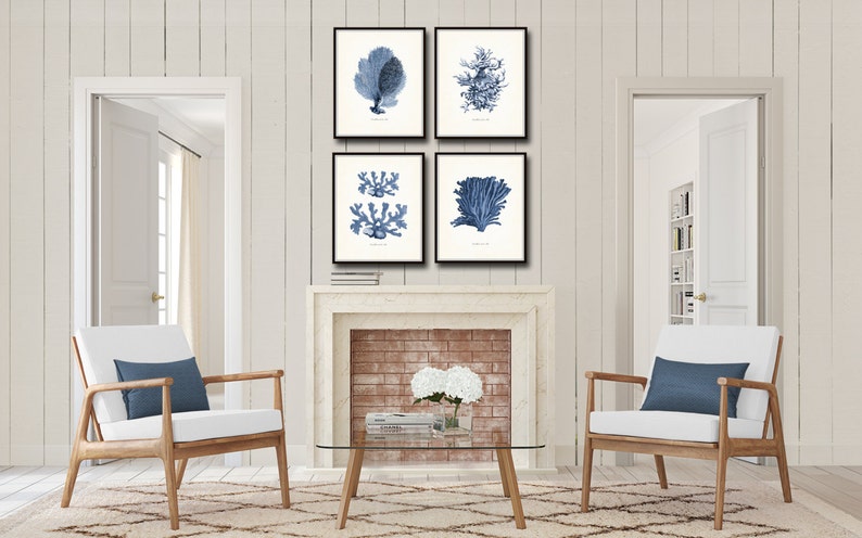 Op de afbeelding: Vier ingelijste prints van blauwe en witte illustraties van koraal en zeewier. De prints zijn gerangschikt in een rasterpatroon op een witte bakstenen open haard.