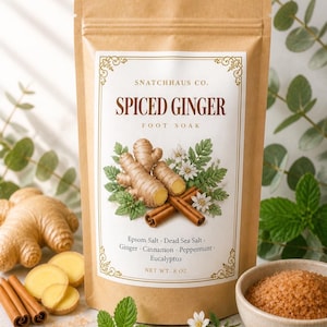 May include: A brown paper pouch of Snatchhaus Co. Spiced Ginger foot soak with a net weight of 8 oz. The label features illustrations of ginger root, cinnamon sticks, and white flowers, listing ingredients including Epsom salt and Dead Sea salt.