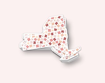 May include: A stack of New York state outline stickers with a floral pattern in shades of pink, red, and cream.