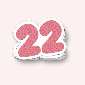 May include: A sticker with the number 22 in a pink color with a red floral pattern.