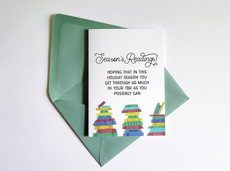 The TBR List card by LuckyDogMailClub is a white card with the title in cursive and 3 colorful stacks of books to show that the TBR list is huge.