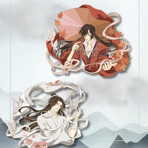 May include: Two decorative enamel pins featuring anime-style characters. The top pin shows a figure in red robes holding a large umbrella surrounded by maple leaves and butterflies. The bottom pin depicts a figure in white robes with butterflies and flowers.