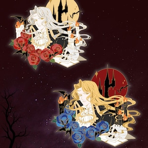 May include: Two enamel pins featuring a long-haired figure with a ruffled collar, surrounded by roses, lit candles, a skull, and a castle silhouette against a circular background. One pin has red roses and a yellow moon, the other has blue roses and a red moon.