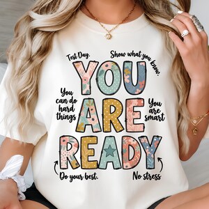 Puede incluir: Una camiseta de color crema con el texto "YOU ARE READY" en letras grandes y multicolores con patrones florales y de lunares. El texto circundante incluye "Test Day," "Show what you know," "You can do hard things," "You are smart," "Do your best," y "No stress."