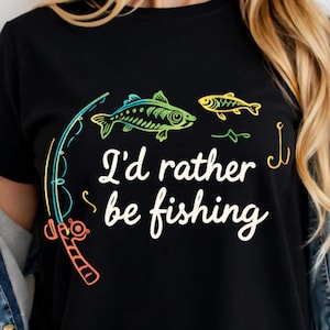 Op de afbeelding: Zwart t-shirt met de tekst "I'd rather be fishing" in witte letters. Het shirt heeft kleurrijke illustraties van een hengel, vissen en een haak. Een casual ontwerp voor visliefhebbers.