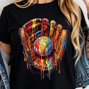 May include: A black t-shirt featuring a graphic print of a brown leather baseball glove holding a baseball. Both the glove and the ball are covered in vibrant, dripping paint in shades of red, yellow, and blue, with colorful sprinkles on the ball.