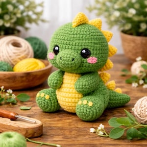 Puede incluir: Un dinosaurio de ganchillo hecho a mano en verde y amarillo. El dinosaurio tiene grandes ojos negros, mejillas rosas y púas amarillas en la espalda. El juguete está sobre una superficie de madera, con hilo y plantas en el fondo.