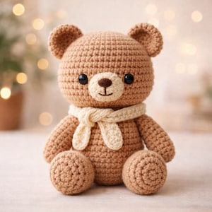 Könnte beinhalten: Ein handgehäkelter Teddybär in Brauntönen. Der Bär hat schwarze Knopfaugen, eine hellbraune Nase und einen cremefarbenen Schal. Der Bär sitzt mit ausgestreckten Armen und Beinen. Der Hintergrund ist unscharf mit Bokeh-Lichtern.