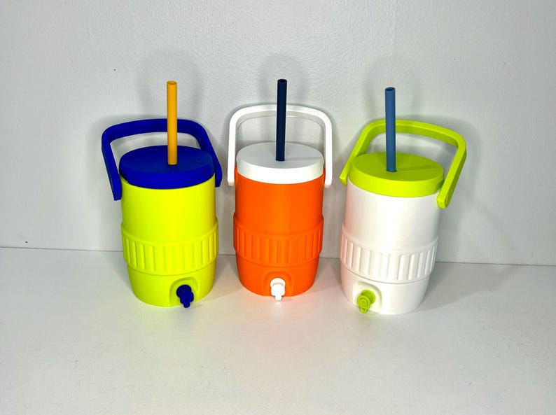 May include: Three colorful water coolers with lids and handles. The coolers are yellow with a blue lid and handle, orange with a white lid and handle, and white with a green lid and handle. Each has a straw and a spigot.